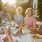 Seniors sitting at an outdoor dining area at our 55 and over community in Noblesville, featuring a table with food and drink.