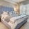 Model bedroom at our senior living apartments for rent in Noblesville, IN, featuring windows with curtains and blinds.