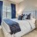 Model bedroom at our senior living apartments for rent in Noblesville, IN, featuring windows with curtains and blinds.